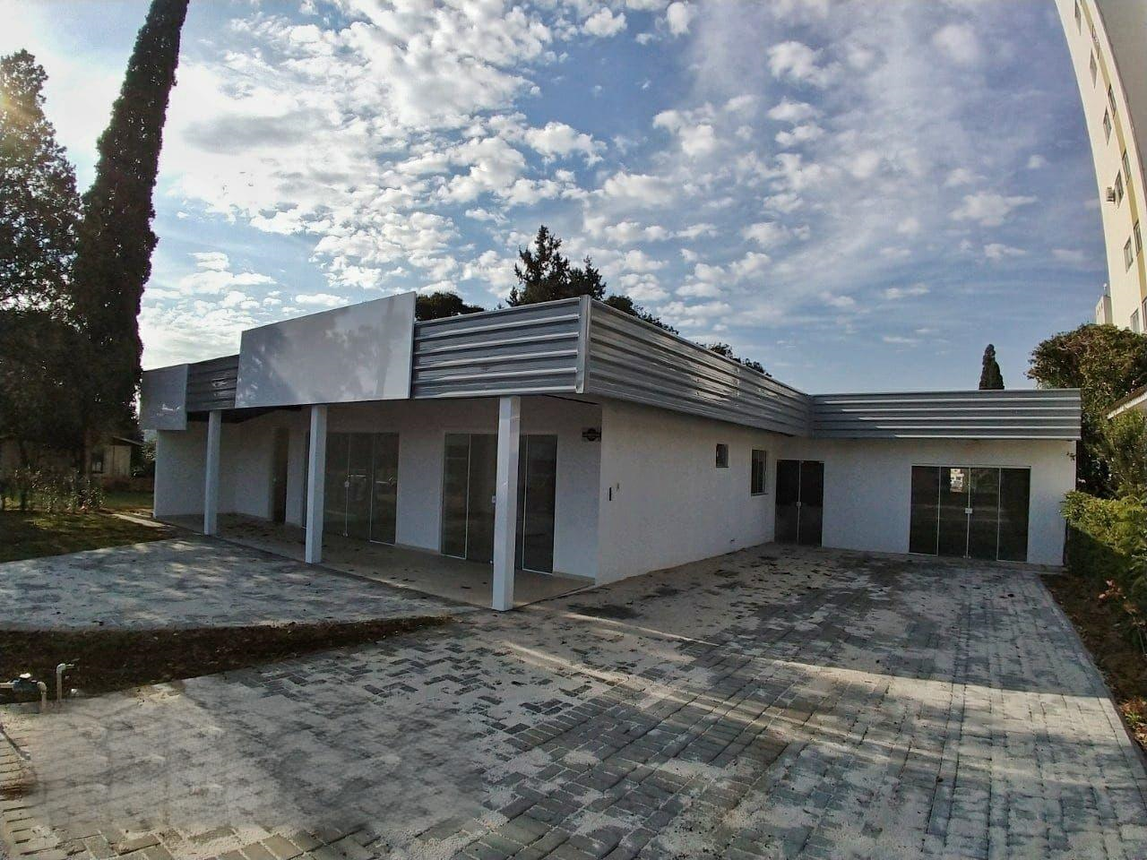 Casa branca, telhado de zinco, portas de vidro quintal pavimentado com pedras