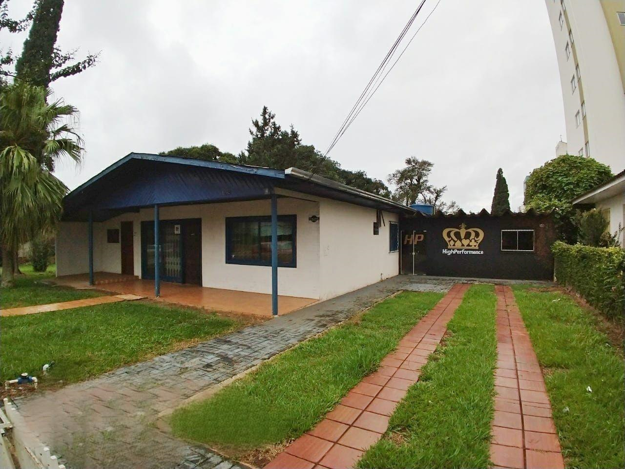 Casa bege, telhado azul, quintal gramado verde com caminho para carro na lateral direita.